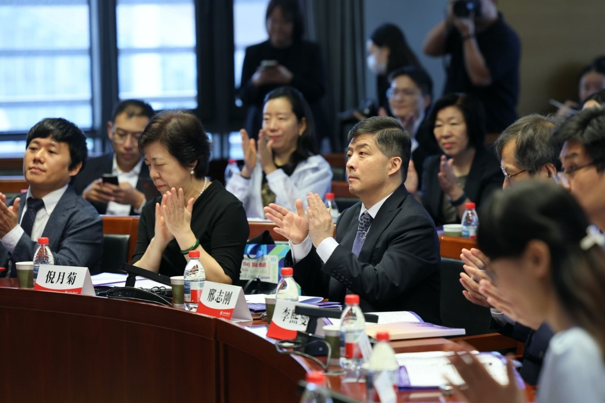 Xing Zhigang (center), an editorial member of China Daily, joins other experts in applauding the opening of the forum. WANG ZHUANGFEI/CHINA DAILY
