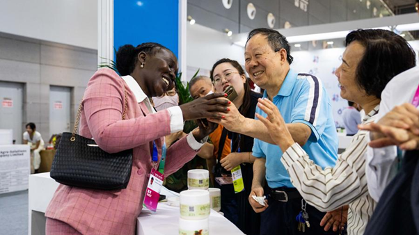 An exhibitor (L) chats with visitors during the fourth China-Africa Economic and Trade Expo